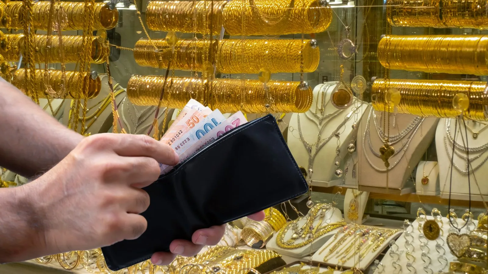 Geldbörse mit Banknoten vor Goldschmuck