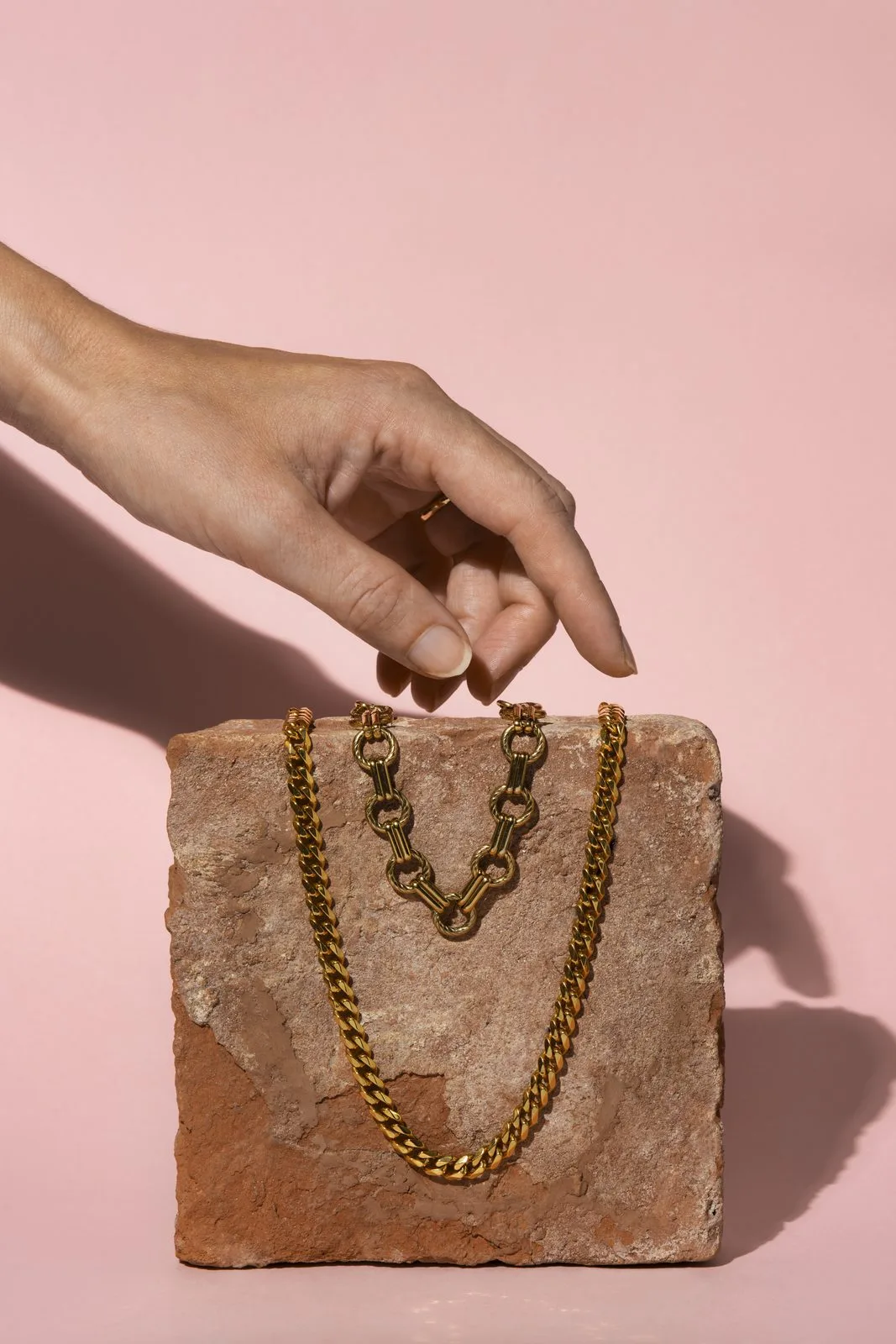 Hand greift nach goldener Panzerkette auf Steinblock