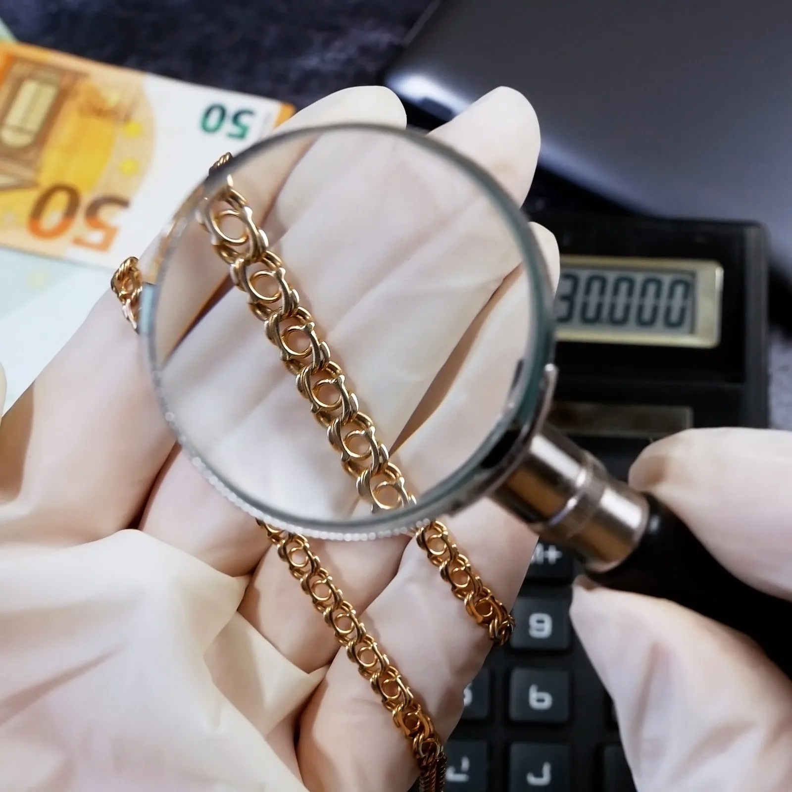 Goldkette wird mit Lupe geprüft